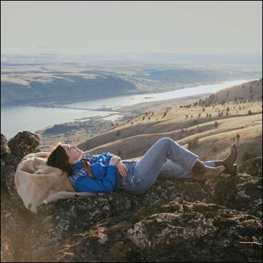 A person lying on a rock with a blanket on her back
AI-generated content may be incorrect.