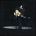 A person playing guitar on stage
Description automatically generated