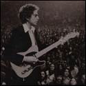 A person holding a guitar in front of a crowd
Description automatically generated