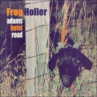 A goat with horns sticking out of the grass

Description automatically generated