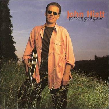 A person holding a guitar in a field
Description automatically generated