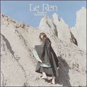 A person in a long dress standing on a rocky hill
Description automatically generated