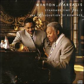 A person in a suit looking at a person playing a piano
Description automatically generated