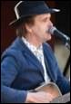 A person in a hat with a guitar in his mouth

Description automatically generated with medium confidence