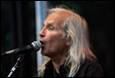A person with long hair singing into a microphone

Description automatically generated