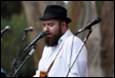A person with a beard and hat singing into microphones

Description automatically generated with low confidence