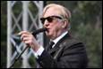 A person in a suit and sunglasses holding a microphone

Description automatically generated with medium confidence