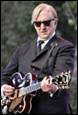 A person in a suit playing a guitar

Description automatically generated with medium confidence