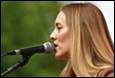 A person with blonde hair singing into a microphone

Description automatically generated