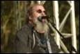 A person with a beard singing into a microphone

Description automatically generated