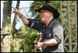 A person in a cowboy hat holding a guitar and pointing

Description automatically generated