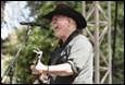 A person in a cowboy hat singing into a microphone

Description automatically generated