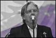 A person in a suit singing into a microphone

Description automatically generated