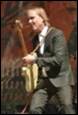 A person in a suit playing a guitar

Description automatically generated