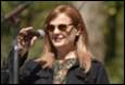A person with sunglasses holding a microphone

Description automatically generated