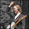 A person holding a guitar and raising his hand

Description automatically generated