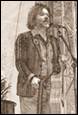 A person holding a guitar and standing next to a microphone

Description automatically generated