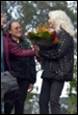 A person holding flowers and another person standing next to a person

Description automatically generated