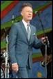 A person in a suit holding a microphone

Description automatically generated