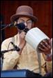 A person in a hat speaking into a microphone

Description automatically generated