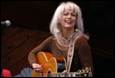 A person with white hair and a guitar

Description automatically generated