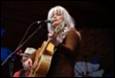 A person with white hair playing guitar

Description automatically generated
