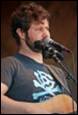 A person with a guitar and microphone

Description automatically generated