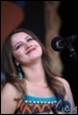 A person with long hair and a microphone

Description automatically generated