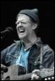 A person with a hat and a guitar

Description automatically generated