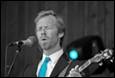 A person in a suit and tie singing into a microphone

Description automatically generated