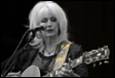 A person with white hair playing guitar

Description automatically generated