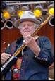 A person in a cowboy hat playing a guitar

Description automatically generated
