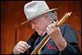 A person in a hat playing a guitar

Description automatically generated