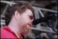 A person with a beard and a microphone

Description automatically generated