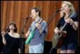 A group of people singing and playing instruments

Description automatically generated