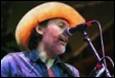 A person wearing a cowboy hat singing into a microphone

Description automatically generated