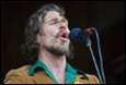A person with a beard singing into a microphone

Description automatically generated
