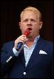 A person in a suit holding a microphone

Description automatically generated
