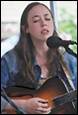A person with a guitar and a microphone

Description automatically generated