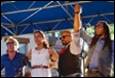 A group of people standing in front of a blue tent

Description automatically generated