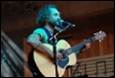A person playing guitar on a stage

Description automatically generated