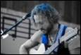 A person playing guitar and singing into a microphone

Description automatically generated