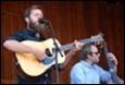A person playing a guitar and singing

Description automatically generated