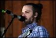 A person with a beard singing into a microphone

Description automatically generated