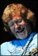 A person with curly hair and glasses laughing

Description automatically generated