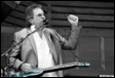 A person holding a guitar and raising his fist

Description automatically generated