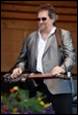 A person in sunglasses and a grey jacket holding a guitar

Description automatically generated