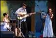 A person playing a guitar on a stage

Description automatically generated