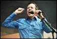 A person holding a microphone and raising his hands

Description automatically generated