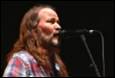 A person with long hair and beard singing into a microphone

Description automatically generated